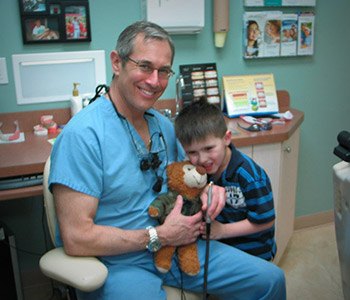 Dr. Brooks giving young child stuffed bear