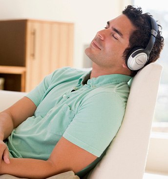 man lying down, relaxing, and listening to music