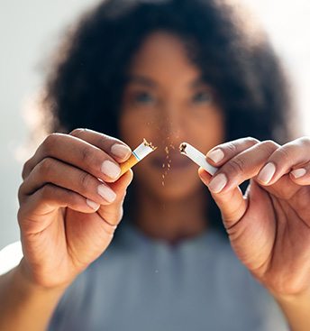 woman breaking a cigarette showing she’s quitting