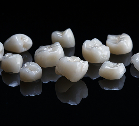 Several tooth colored dental crowns on a black background