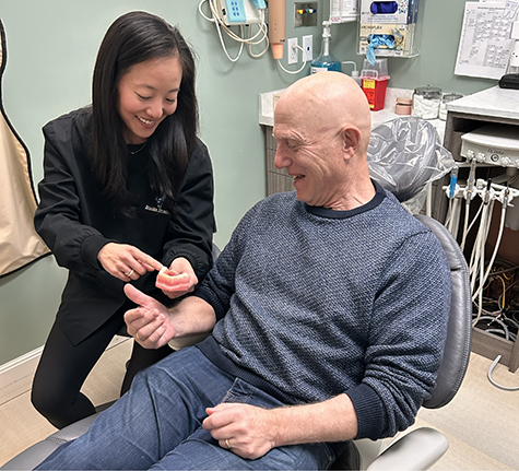 Cosmetic dentist showing a patient a model of the teeth
