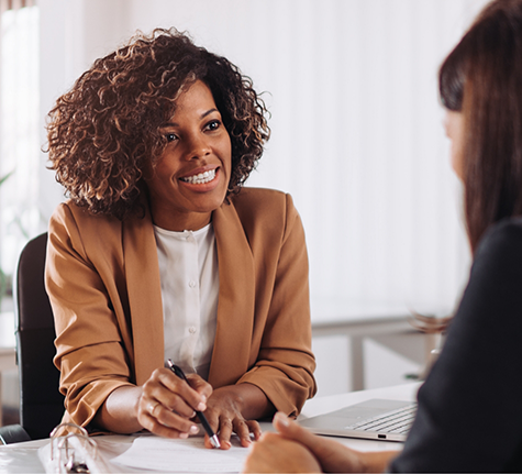 Two women having a discussion at a table in an office