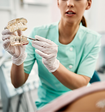 Dentist showing a model of a mouth with a dental implant to a patient