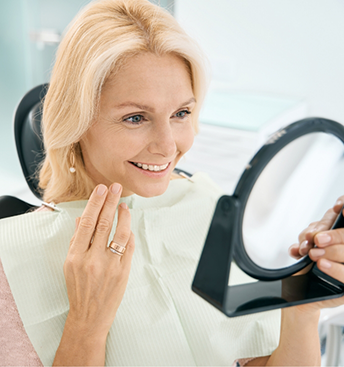 Dental patient admiring her smile in a mirror