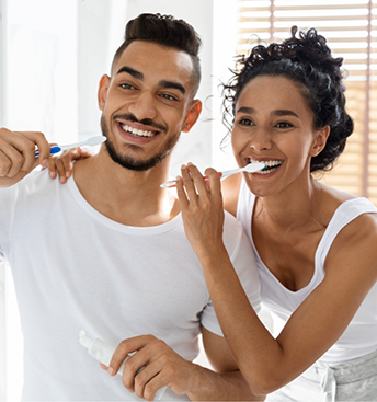 Young man and woman brushing their teeth