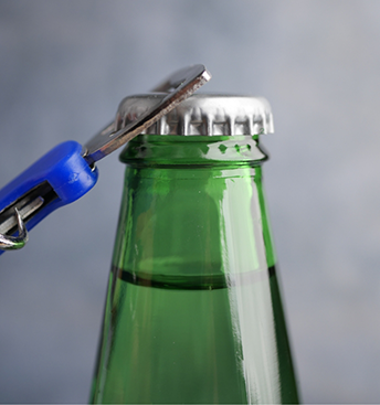 Person using a bottle opener on a glass bottle