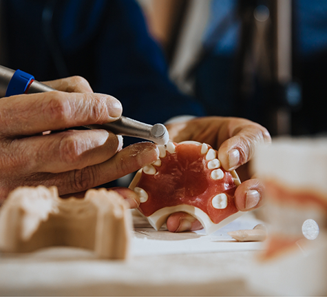 Dental lab technician adjusting a denture