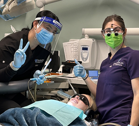 Two Brooks Dental team members giving thumbs up with a patient