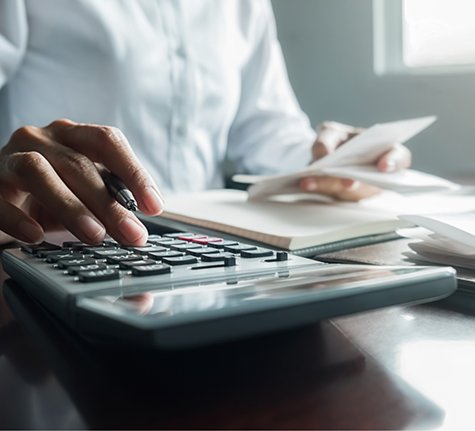 Person typing on a calculator and filling out paperwork
