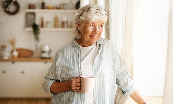 Senior woman with a coffee mug looking out her window