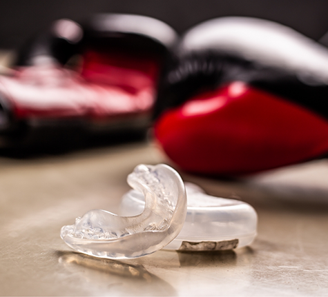 Clear mouthguard laying next to a pair of red boxing gloves