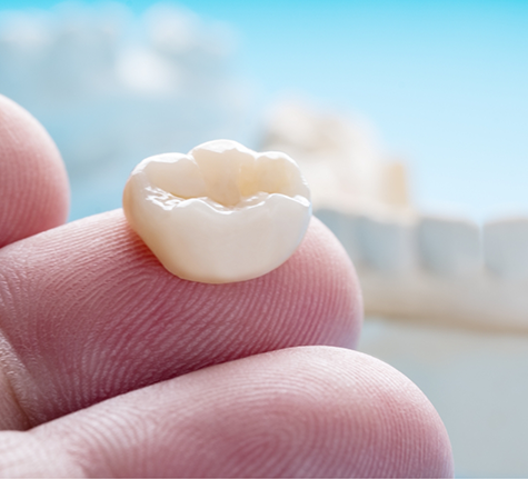 Close up of a dental crown on a person's finger