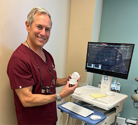 Doctor Howard smiling while holding a model of the teeth