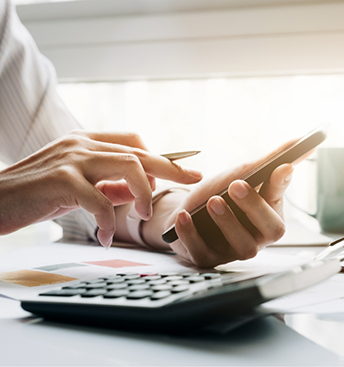 Person sitting at a desk and typing on a calculator