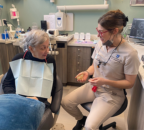 Brooks Dental team member showing a model of a denture to a patient