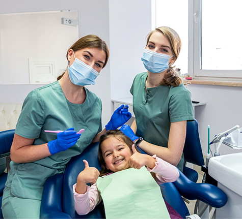 Smiling girl giving two thumbs up at her dental visit