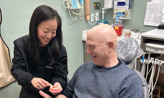 Dentist smiling while showing a patient a model of the teeth