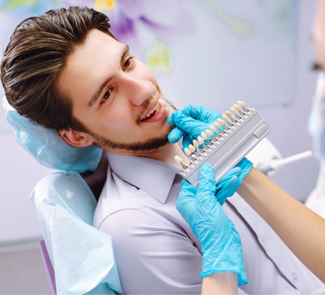 Dentist holding veneers to a patient's teeth