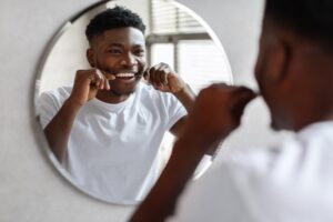 man flossing in front of a mirror